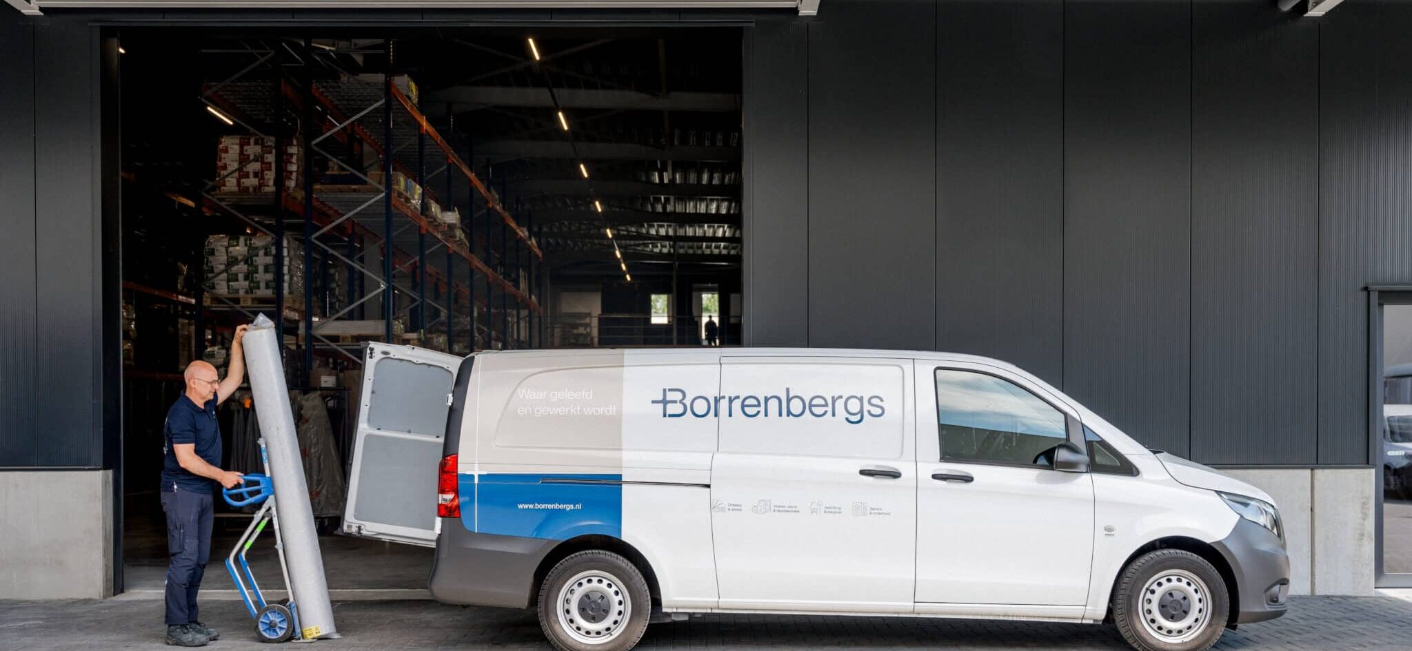 Magazijnmedewerker van Borrenbergs laadt bus in met materialen voor interieuradvies en projectinrichting